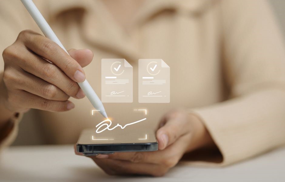 Pessoa assinando digitalmente um documento no smartphone, com ícones de contratos com checkmark flutuando ao lado, simbolizando assinatura eletrônica e assinatura digital.