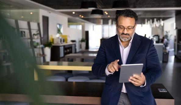 Executivo de negócios usando tablet em um ambiente de escritório moderno e bem iluminado, representando inovação no mercado de trabalho.