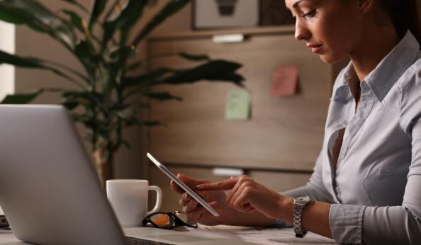 Mulher em escritório utilizando tablet para realizar assinatura eletrônica em documentos digitais, transmitindo segurança e validade jurídica no ambiente corporativo.