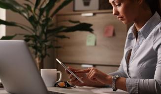 Mulher em escritório utilizando tablet para realizar assinatura eletrônica em documentos digitais, transmitindo segurança e validade jurídica no ambiente corporativo.